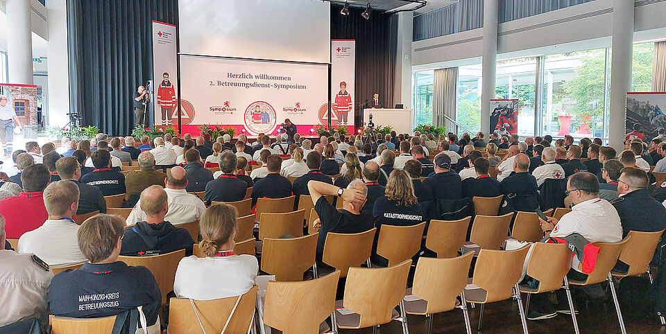 Teilnehmende sitzen im Saal der Wandelhalle Bad Wildungen und schauen in Richtung Bühne