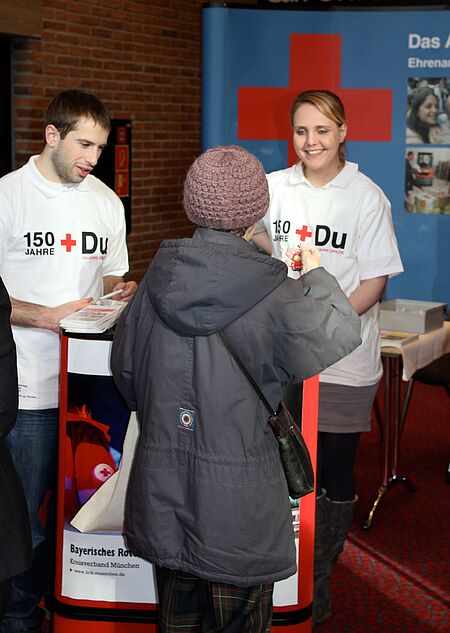 Zwei Mitarbeiter des Roten Kreuzes erzählen einer Messebesucherin von den vielfältigen Möglichkeiten im Verein
